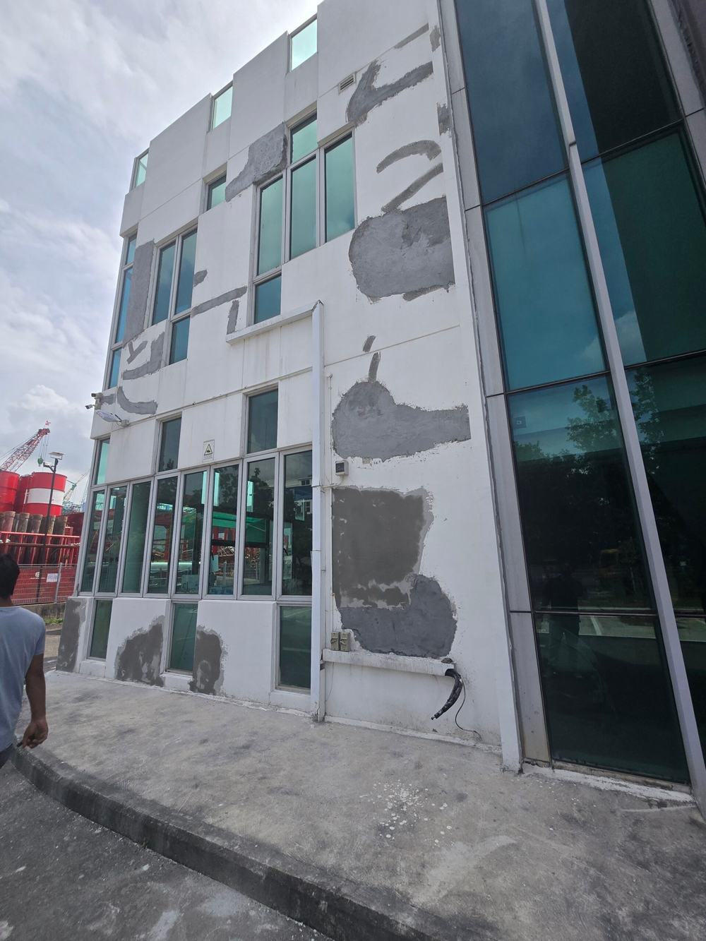 Singapore commercial building facade covered in grey cement render patches before repainting, 5 January 2026