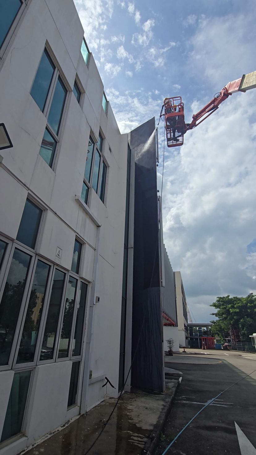 Eco Painting Service painter high-pressure washing a commercial facade from a boom lift
